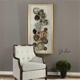 collection of hand painted multicolored plates, artfully arranged over a white backing, mounted in a pine wood shadow box
