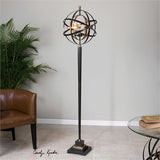 Metal armillary sphere finished in a dark oil rubbed bronze and french gold leaf sitting on top of a sleek tapered base. 