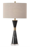 Mid-century flair is added to this design featuring an hour glass shaped base constructed of solid, black marble and is accented with stainless steel details finished in a plated gold and a thick crystal foot. The oval hardback drum shade is a beige linen fabric with vertical slubbing.
